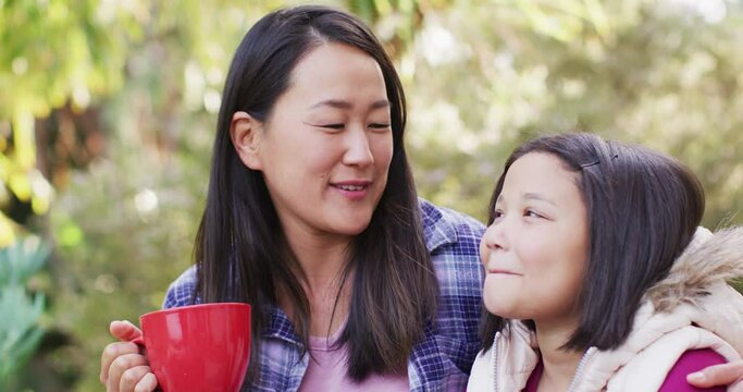 Video of happy asian mother and daughter embracing and talking in garden