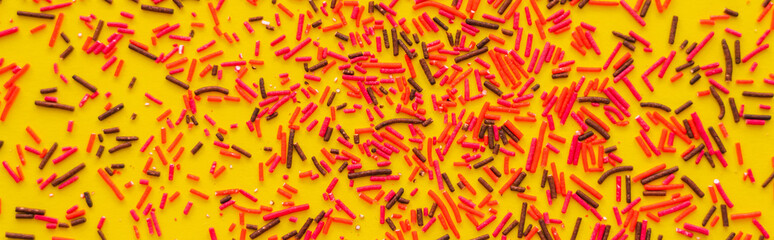 Fototapeta na wymiar Top view of red and black sprinkles on yellow background, banner.