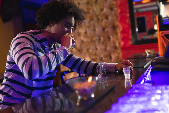 African american man sitting at the bar drinking shots in a bar