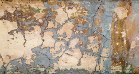 Obraz na płótnie Canvas Shot of a wall with cracked plaster - stock photo. Vintage photograph of an old shabby wall with cracks covered with cement - an image for an artistic background. Soft warm light.