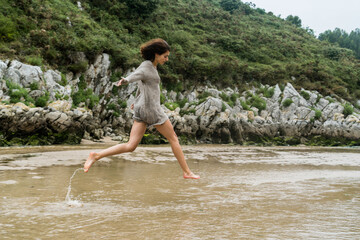Young caucasian girl playing around in a river mouth in cantabrian water.