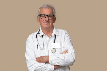 Older doctor in eyeglasses with stethoscope and white uniform on light brown background.