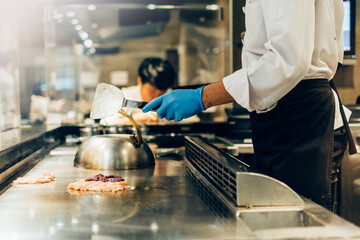 Hand of man take cooking of meat with vegetable grill, Chef cooking wagyu beef in Japanese teppanyaki restaurant