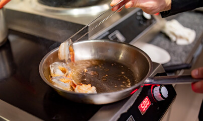 man chef cooking tasty shrimp in frying pan on kitchen
