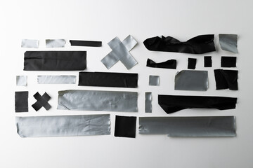 Ripped up pieces of black and silver tape on white background