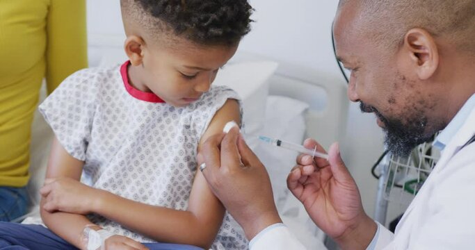 African american male doctor vaccinating child patient at hospital