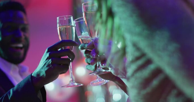 Video of a diverse group of happy friends making a toast with glasses of champagne at a nightclub