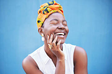 Happy black woman, african fashion and culture with turban scarf on blue wall background in...