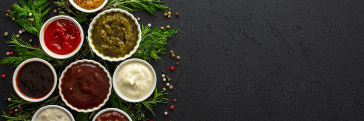 Different types of sauces in bowls with seasonings banner, rosemary and dill, thyme and and peppercorns, top view, copy space