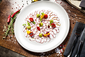 Octopus carpaccio. Spinach cream, cherry tomatoes. Delicious healthy Italian traditional food closeup served for lunch in modern gourmet cuisine restaurant