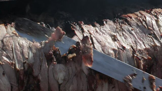 Chef is cutting cag kebab with knife slices or pieces of meat drops down as chef cuts