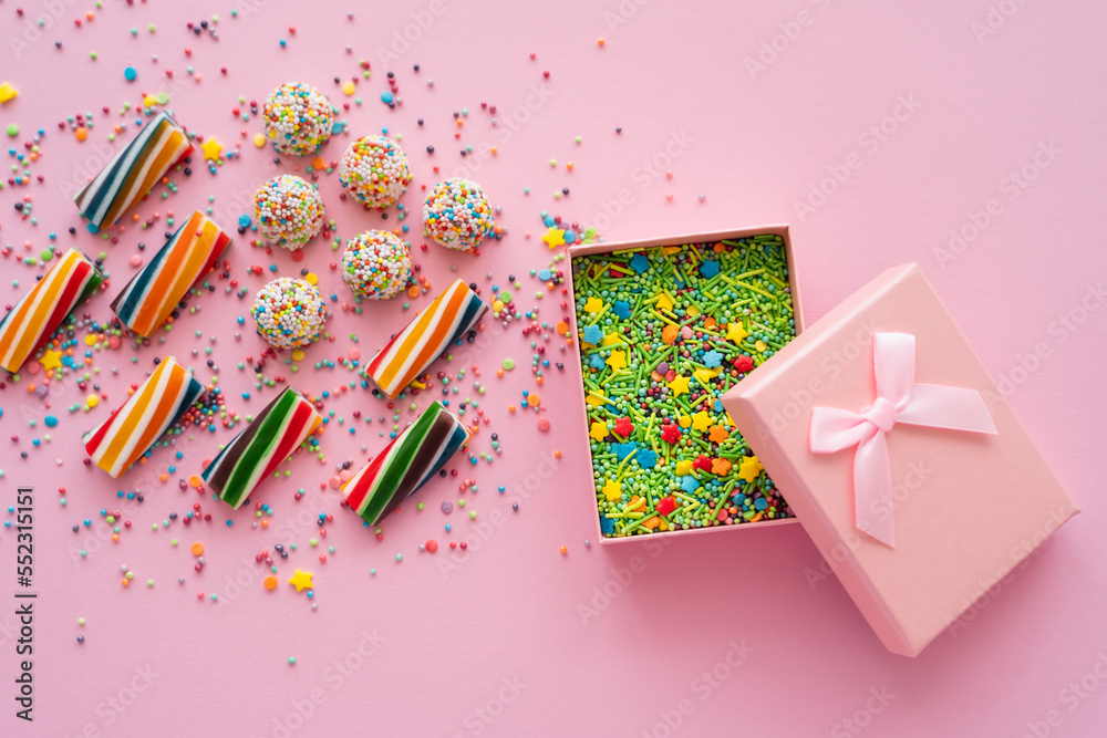 Canvas Prints top view of colorful sweets near gift box with sprinkles on pink background.