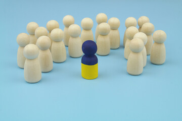 One leader with colors of Ukrainian flag and wooden people figures on blue background,