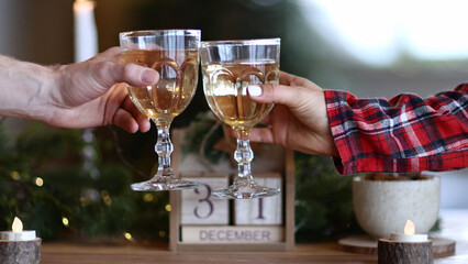 Couple clinking glasses of champagne over the New Year's table next the Christmas wooden calendar with numbers of 31st. slow motion