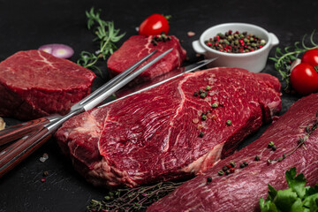 Variety of fresh raw beef steak with spices for grilling on a dark background. Whole piece of steaks ready to cook. banner, menu, recipe place for text, top view
