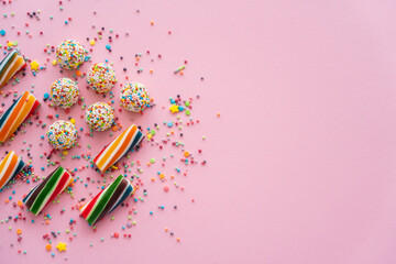 Top view of different colorful sweets and sprinkles on pink background with copy space.