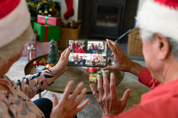 Senior caucasian couple having christmas video call with diverse people