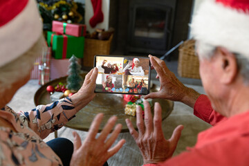 Senior caucasian couple having christmas video call with diverse people
