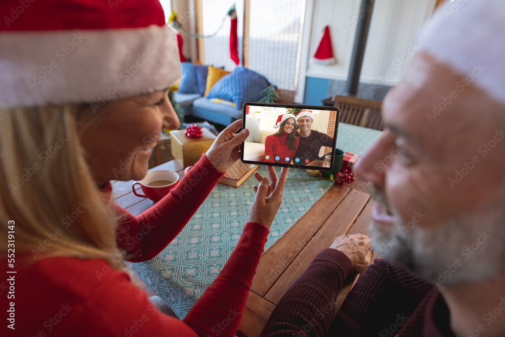 Sticker Caucasian couple with santa hats having christmas video call with happy caucasian couple