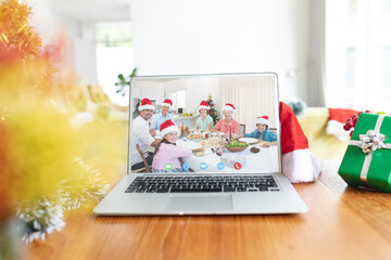 Happy caucasian family with santa hats and christmas decorations having christmas laptop video call