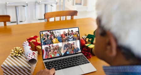 Biracial man with santa hat having video call with happy diverse friends