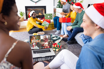 Diverse friends with christmas decorations having video call with happy caucasian friends