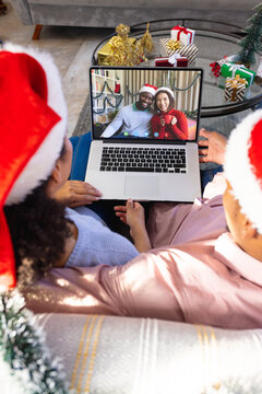 Biracial couple with christmas decorations having video call with happy diverse couple