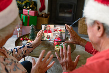 Senior caucasian couple with santa hats having video call with happy caucasian children