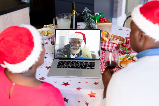 African american couple with santa hats having video call with happy african american man