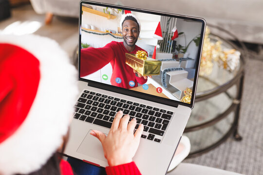Caucasian woman with santa hat having video call with happy african american man