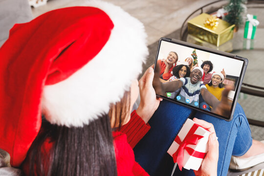 Caucasian woman with santa hat having video call with happy diverse friends
