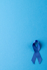 Vertical of blue ribbon for prostate cancer awareness, on blue background with copy space
