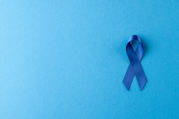 Composition of blue ribbon for prostate cancer awareness, on blue background with copy space