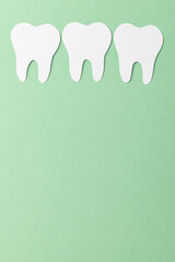 Vertical composition of white teeth on green background with copy space