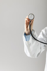 Midsection of caucasian doctor holding stethoscope on grey background with copy space