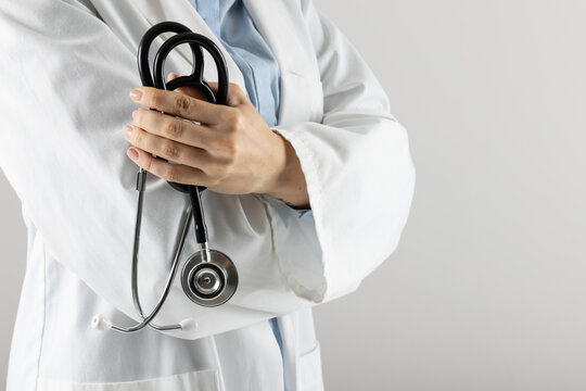 Midsection of caucasian doctor holding stethoscope on grey background with copy space - Powered by Adobe