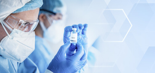 research scientist holding vaccine bottle in hand on modern clinical laboratory background