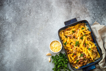 Pasta penne with minced meat, cheese and creamy sauce. Mac and cheese. Top view on stone table.