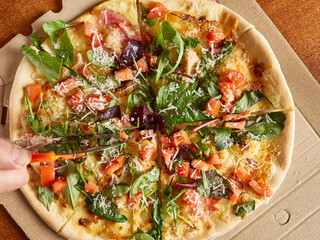 Freshly baked pizza is cut into pieces with a disk knife. View from above.