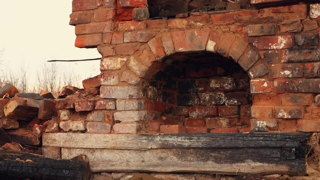 The facade of the destroyed red brick oven, the remains of a burnt house. An abandoned building, a consequence of the war, bombing, missile strikes. Ruins, people in evacuation. UHD 4K.