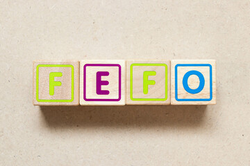 Color letter block in word FEFO (Abbreviation of first expired first out) on wood background