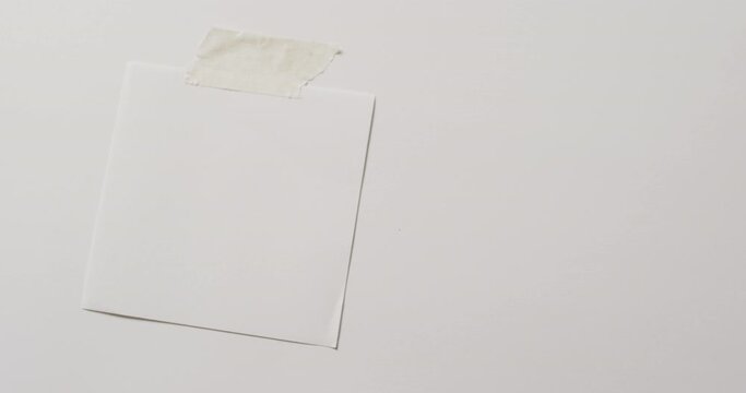 Video of close up of white memo note with copy space taped to white background