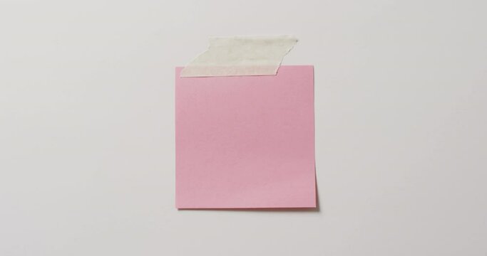 Video of close up of pink memo note with copy space taped to white background