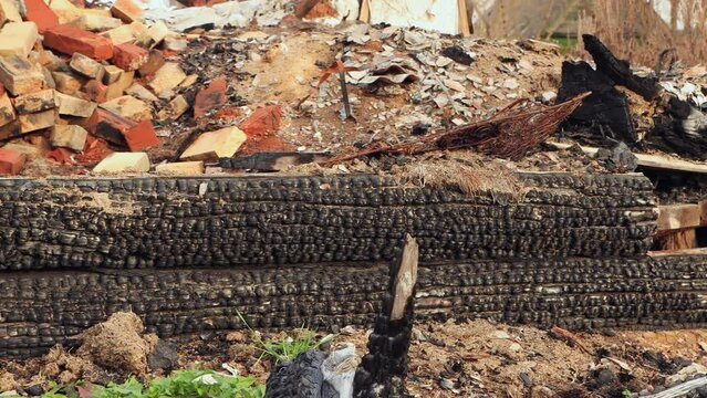 Charred logs of the walls, the remains of a burned-out rural house. An abandoned wooden building, a consequence of the war, bombing, rocket attacks. Ruins, people in evacuation. UHD 4K.