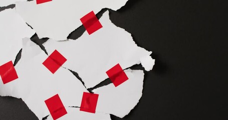 Video of close up of torn pieces of white paper with red tape on black background - Powered by Adobe