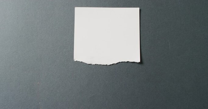 Video of close up of torn piece of white paper on black background