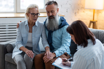 Senior couple, mature man and woman, husband and wife sitting on the sofa on the therapy session at...