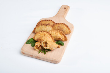 Fried pancakes stuffed with chicken, minced meat, and some spices with parsley leaves