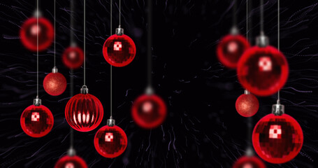 Image of fireworks over christmas baubles on black background