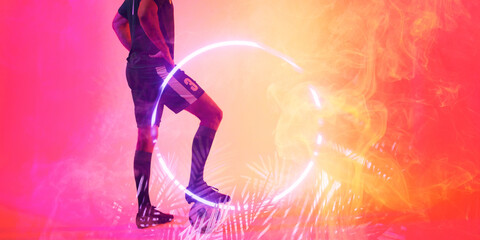 Low section of caucasian male player with leg on ball over illuminated circle and plants, copy space